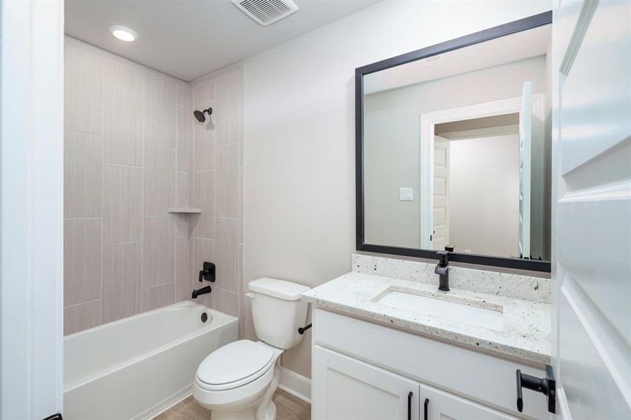 The granite countertops continue into the secondary bathrooms with matte black faucets.