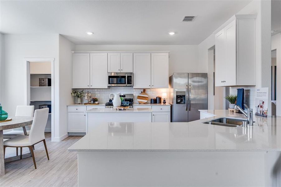 Kitchen with stainless steel appliances, light hardwood / wood-style flooring, white cabinetry, tasteful backsplash, and sink