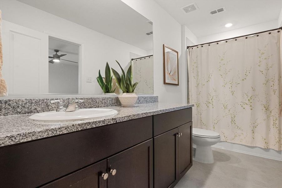 Bathroom with vanity, shower / bath combo, light tile patterned floors, and ceiling fan