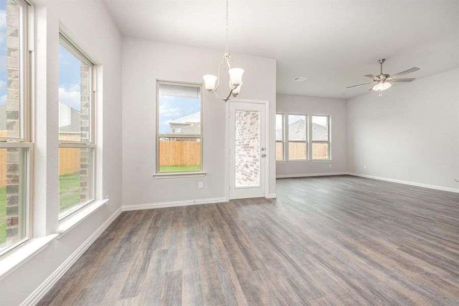 Unfurnished dining area featuring ceiling fan with notable chandelier, dark hardwood / wood-style flooring, and a wealth of natural light