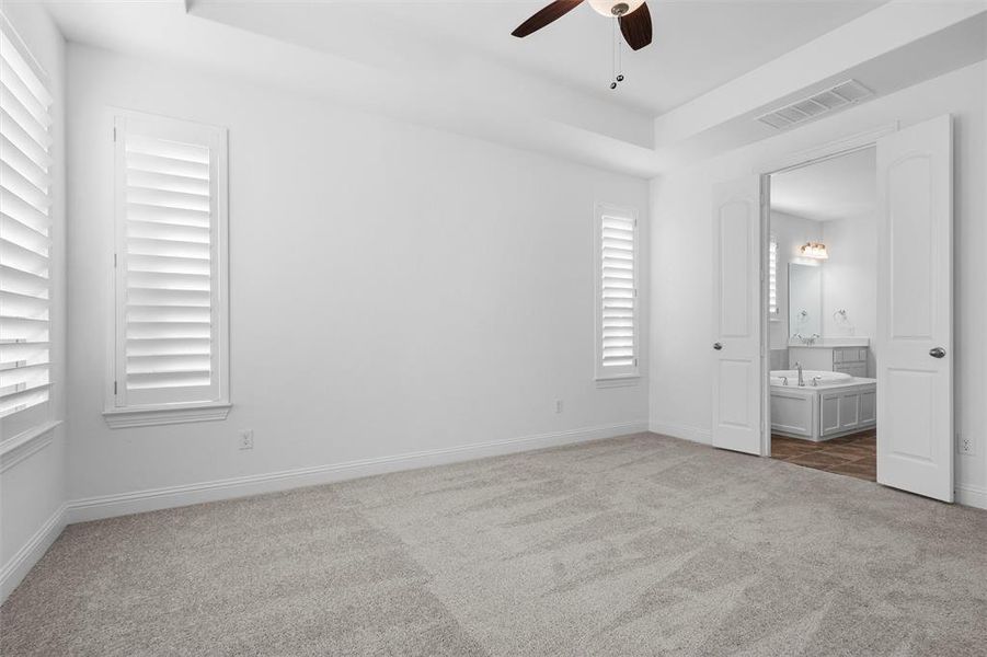 Unfurnished bedroom with ceiling fan, carpet floors, and ensuite bath