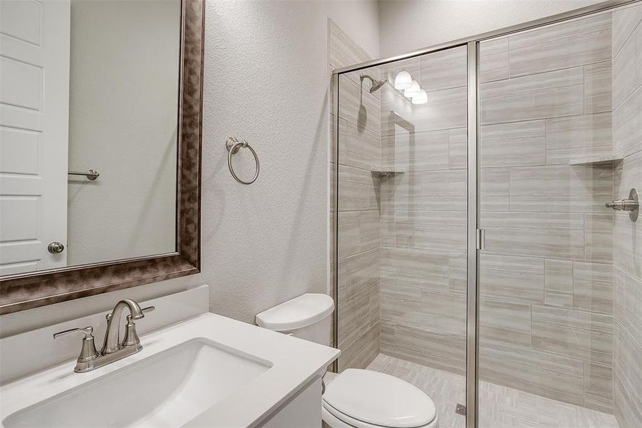 Bathroom featuring vanity, toilet, and a shower with shower door