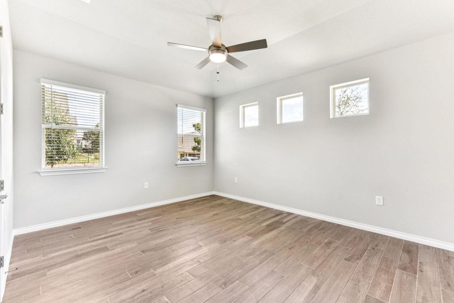 Spare room with plenty of natural light, light wood-type flooring, and a ceiling fan Spare room with plenty of natural light, light wood-type flooring, and a ceiling fan
