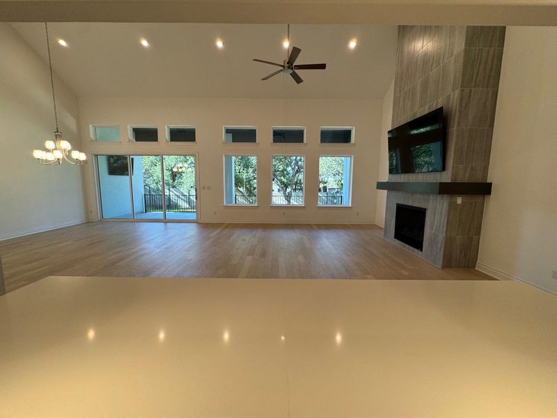 Open concept living room with a gas log fireplace, healthy amount of natural light, a towering ceiling, recessed lighting, and a ceiling fan