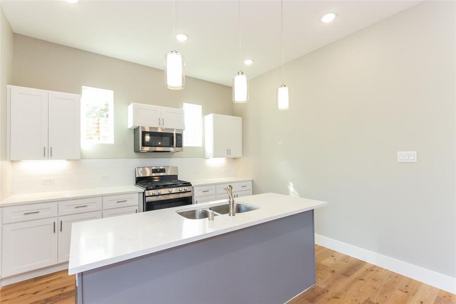 Kitchen with an island with sink, stainless steel appliances, sink, and white cabinetry