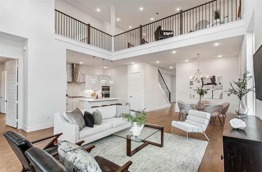 Living room featuring a high ceiling, a chandelier, and light wood-type flooring