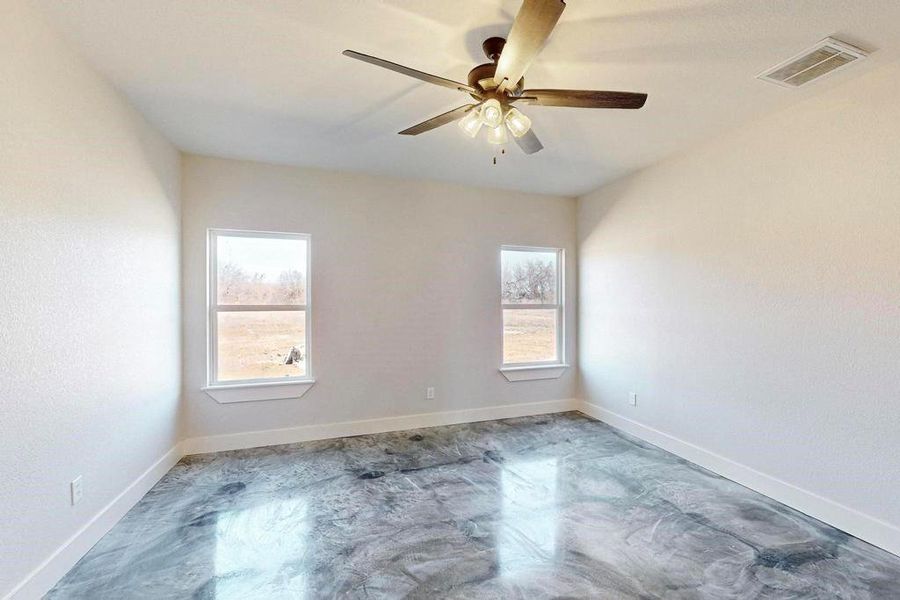 Unfurnished room with finished concrete flooring, baseboards, visible vents, and ceiling fan