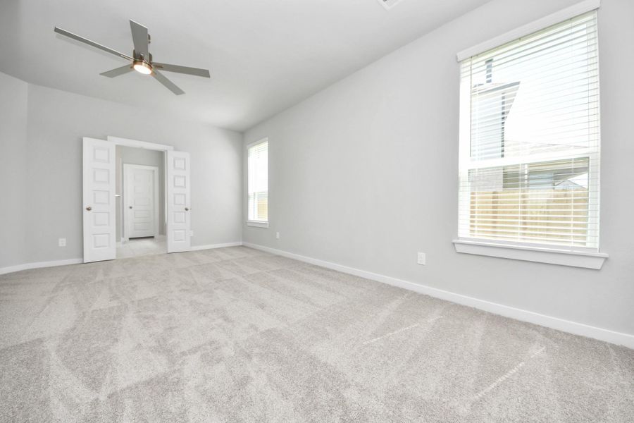 Escape to tranquility in this spacious primary room, adorned with plush carpeting and bathed in the soothing hues of warm paint colors, creating a cozy retreat for relaxation. Sample photo of completed home with similar floor plan. Actual colors and selections may vary. Escape to tranquility in this spacious primary room, adorned with plush carpeting and bathed in the soothing hues of warm paint colors, creating a cozy retreat for relaxation. Sample photo of completed home with similar floor plan. Actual colors and selections may vary.