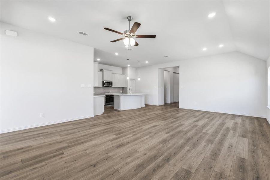 Unfurnished living room with ceiling fan, light wood-style flooring, recessed lighting, and lofted ceiling