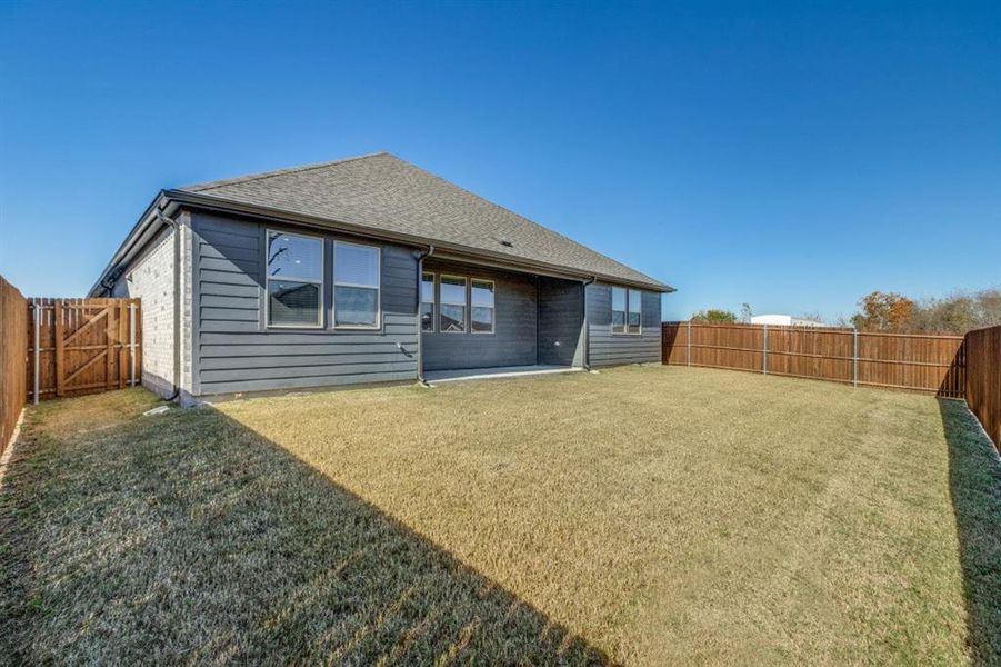 Back of house with a patio, a fenced backyard, roof with shingles, and a gate