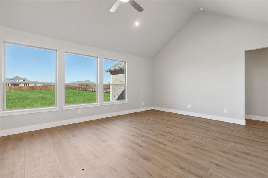 Empty room with ceiling fan, lofted ceiling, and light hardwood / wood-style flooring