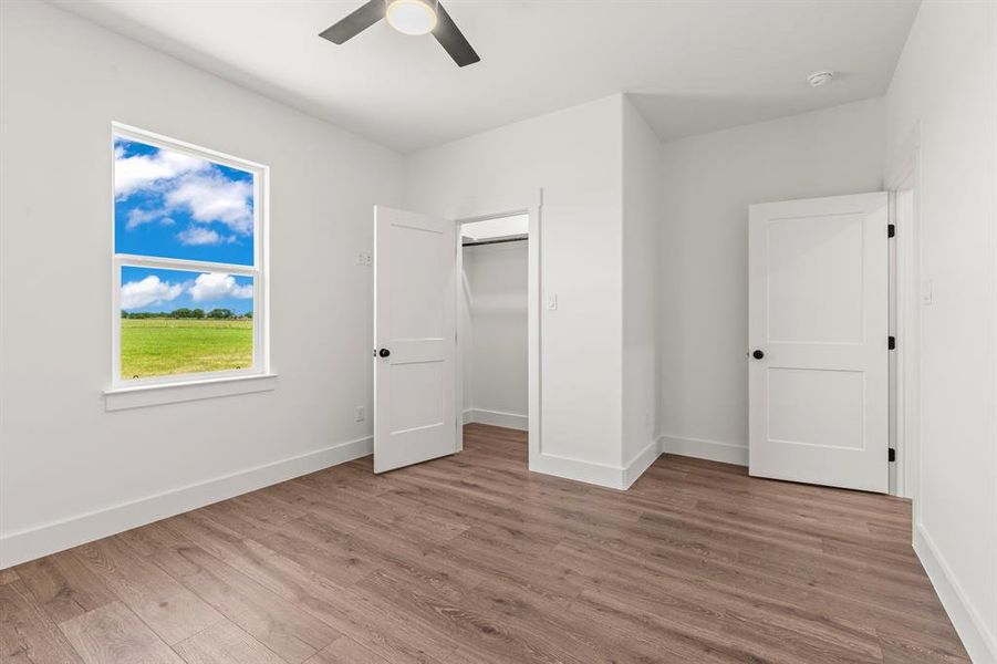Unfurnished bedroom with wood finished floors, ceiling fan, a closet, and a spacious closet