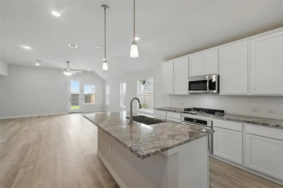 Kitchen with a sink, appliances with stainless steel finishes, vaulted ceiling, tasteful backsplash, and light wood finished floors