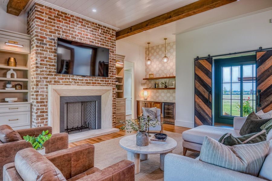 Living area with beamed ceiling, wood finished floors, bar area, wine cooler, and a fireplace Living area with beamed ceiling, wood finished floors, bar area, wine cooler, and a fireplace