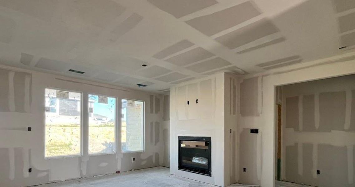 Spacious room with a coffered ceiling, multiple large windows, and a built-in fireplace with a black insert