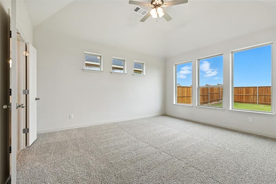 Empty room featuring carpet flooring, vaulted ceiling, and a ceiling fan