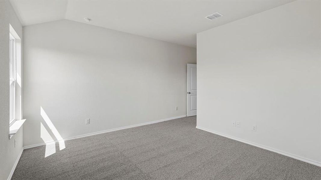 Spacious room featuring vaulted ceilings, a single-hung window, light gray carpeting, neutral wall paint, and white trim