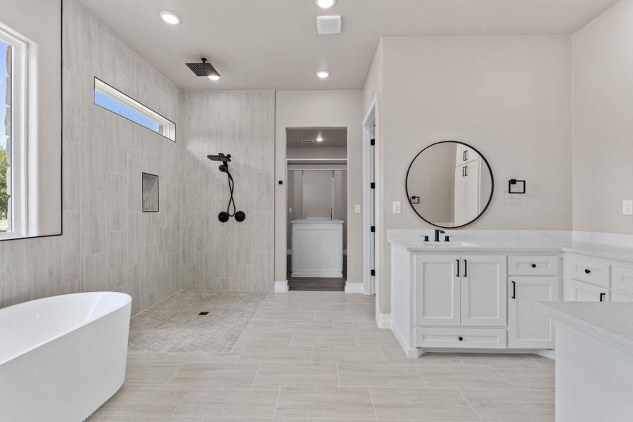 An indulgent primary bath with a spacious walk-in shower and elegant soaking tub. An indulgent primary bath with a spacious walk-in shower and elegant soaking tub.