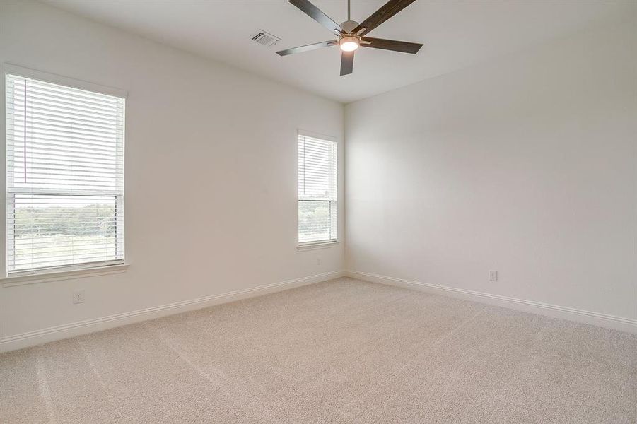 Secondary bedroom with ceiling fan and walk in closet