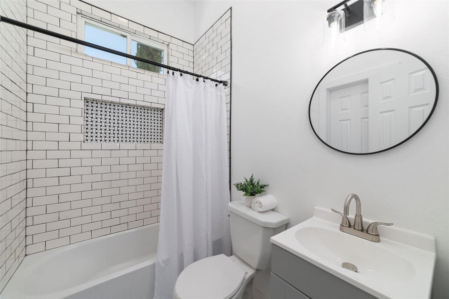 Guest bathroom features a modern design with tile surrounding the tub/shower. Guest bathroom features a modern design with tile surrounding the tub/shower.