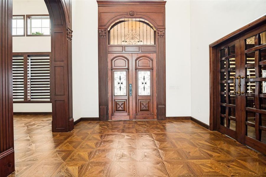 Grand entryway featuring a custom wood-finish double door with glass and wrought iron details