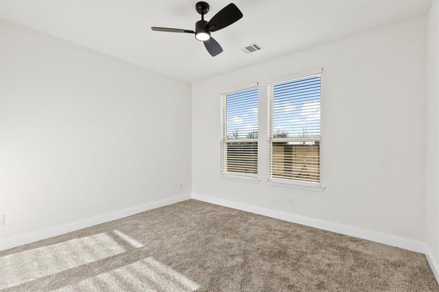 Carpeted empty room featuring visible vents, ceiling fan, and baseboards Carpeted empty room featuring visible vents, ceiling fan, and baseboards