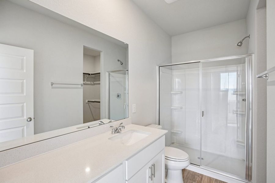 Image of a bathroom with a white dual vanity, a large mirror and a walk-in shower Image of a bathroom with a white dual vanity, a large mirror and a walk-in shower