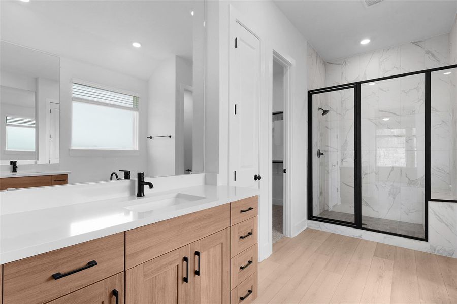 Full bathroom with a marble finish shower, vanity, light wood-style floors, recessed lighting, and a spacious closet