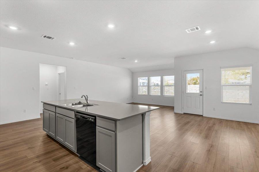 Kitchen featuring open floor plan, a kitchen island with sink, dark wood-style flooring, black dishwasher, and recessed lighting