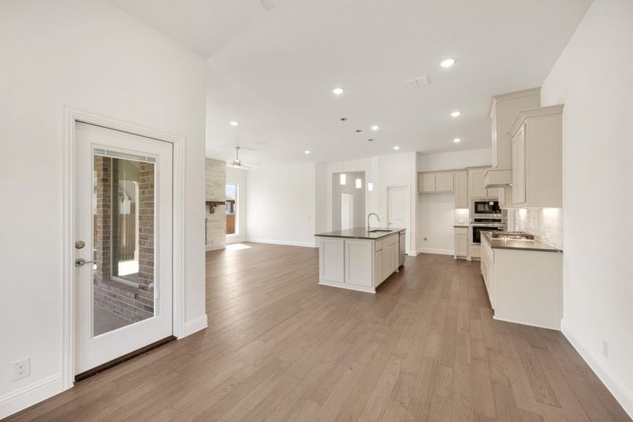 Open-concept kitchen and living area with center island, gray cabinets, hardwood floors, and glass back door