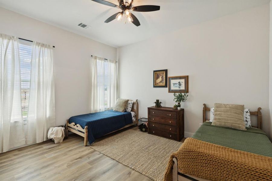 Spacious room featuring wood-finish flooring, light-toned walls, and two large windows with blinds
