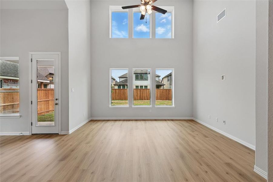 Unfurnished living room featuring visible vents, ceiling fan, a healthy amount of sunlight, and light wood-style floors Unfurnished living room featuring visible vents, ceiling fan, a healthy amount of sunlight, and light wood-style floors