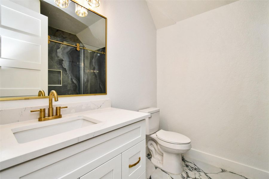 A masterpiece of bath design, this shower features stunning book-matched stone slabs with intricate natural veining. Professional-grade brushed gold hardware and a frameless glass enclosure create a high-end, spa-like experience.