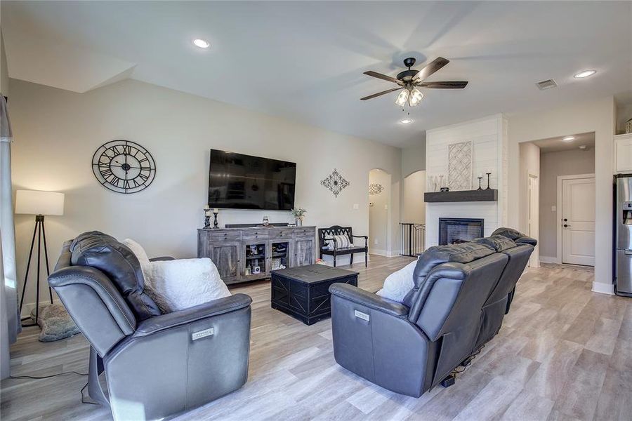 Living room with ceiling fan, a fireplace, and light hardwood / wood-style floors