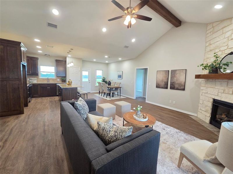Living area featuring a stone fireplace, wood finished floors, a ceiling fan, beamed ceiling, and recessed lighting Living area featuring a stone fireplace, wood finished floors, a ceiling fan, beamed ceiling, and recessed lighting