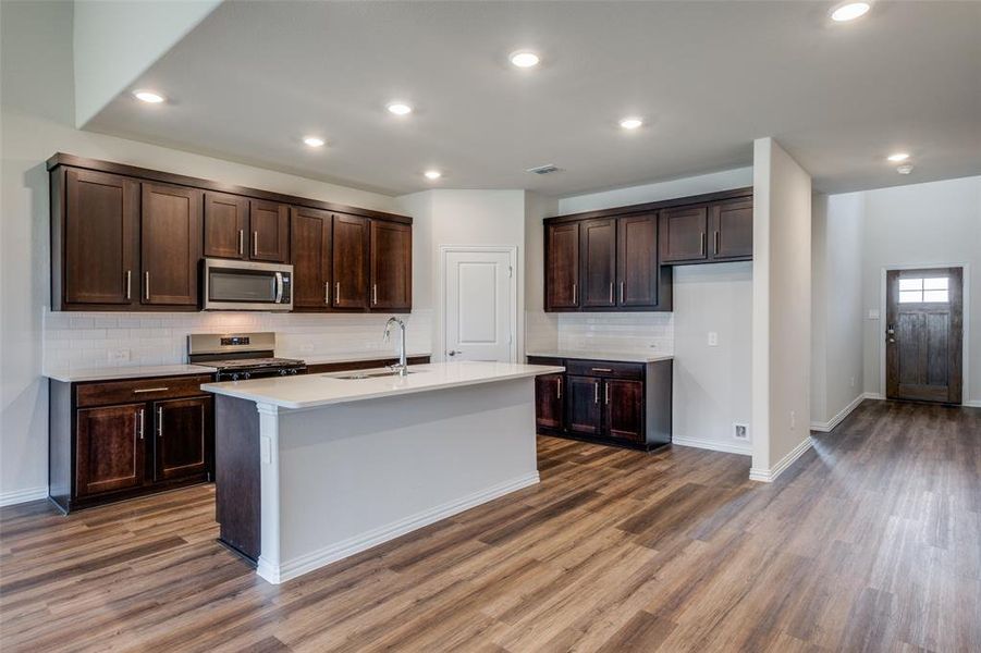 Kitchen with appliances with stainless steel finishes, an island with sink, wood-type flooring, and sink