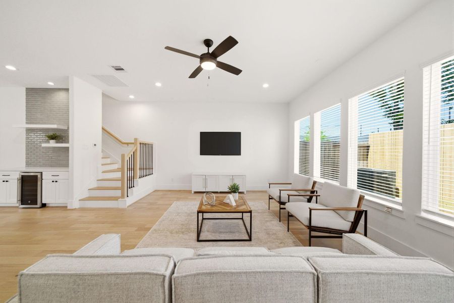 Bright and inviting open-conceptliving room with high ceilings,abundant natural light, andbeautiful wood flooringthroughout. (Photo of a previous build, similar finishes.)