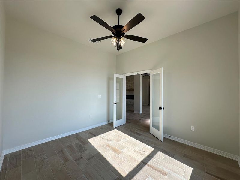 Unfurnished bedroom featuring french doors, wood finish floors, and ceiling fan