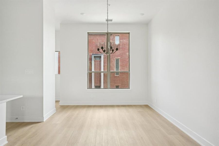 Unfurnished dining area featuring light wood-style flooring, a chandelier, plenty of natural light, and baseboards