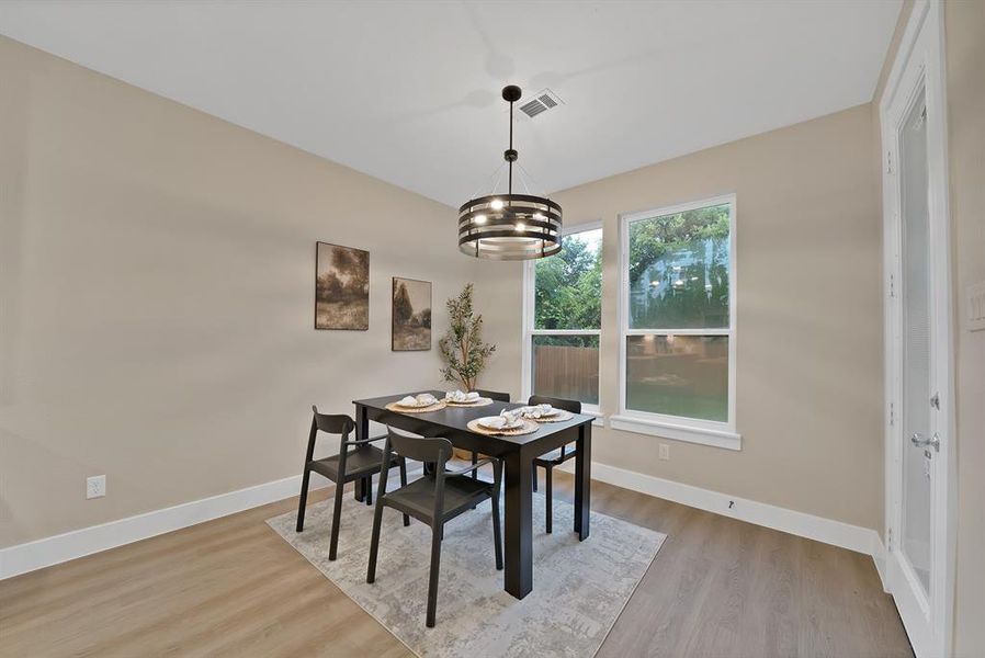 Spacious room featuring wood-finish flooring, tall baseboards, and neutral wall tones Spacious room featuring wood-finish flooring, tall baseboards, and neutral wall tones