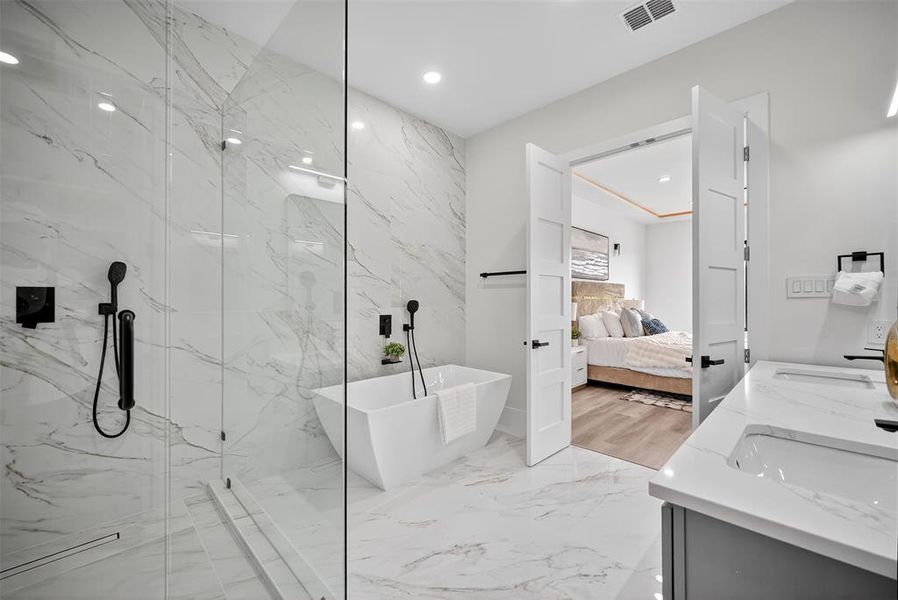 Ensuite bathroom featuring a freestanding tub, double vanity, a marble finish shower, recessed lighting, and light marble finish floors