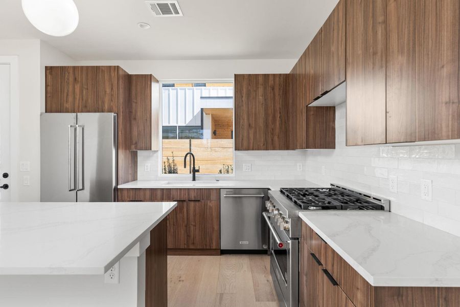 Kitchen featuring a sink, visible vents, high quality appliances, and modern cabinets