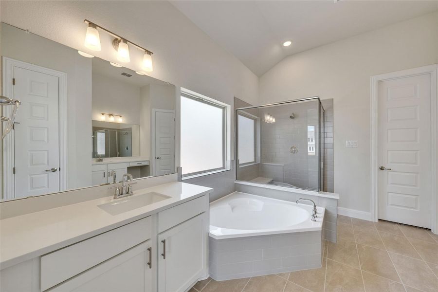 Full bathroom featuring vanity, vaulted ceiling, a bath, a stall shower, and tile patterned floors Full bathroom featuring vanity, vaulted ceiling, a bath, a stall shower, and tile patterned floors
