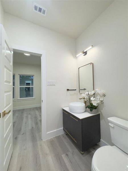 Bathroom with toilet, vanity, and wood-type flooring