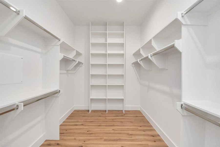 Step into a walk-in closet that defines luxury and functionality. This generously sized space boasts built-in shelving, providing ample room for organization. With high ceilings and recessed lighting, the ambiance is both bright and welcoming.