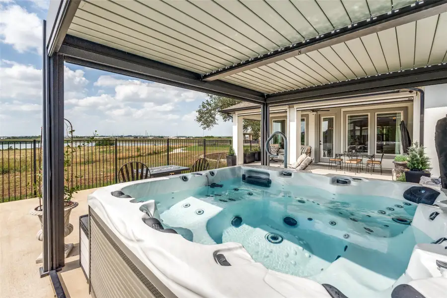 An outdoor hot tub sits under a covered patio structure overlooking the scenic waterfront.