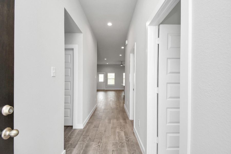 The grand entrance beckons with its soaring ceilings, adorned with elegant wood-look tile flooring featuring sleek oversized baseboards.Sample photo of completed home with similar floor plan. As-built interior colors and selections may vary. The grand entrance beckons with its soaring ceilings, adorned with elegant wood-look tile flooring featuring sleek oversized baseboards.Sample photo of completed home with similar floor plan. As-built interior colors and selections may vary.