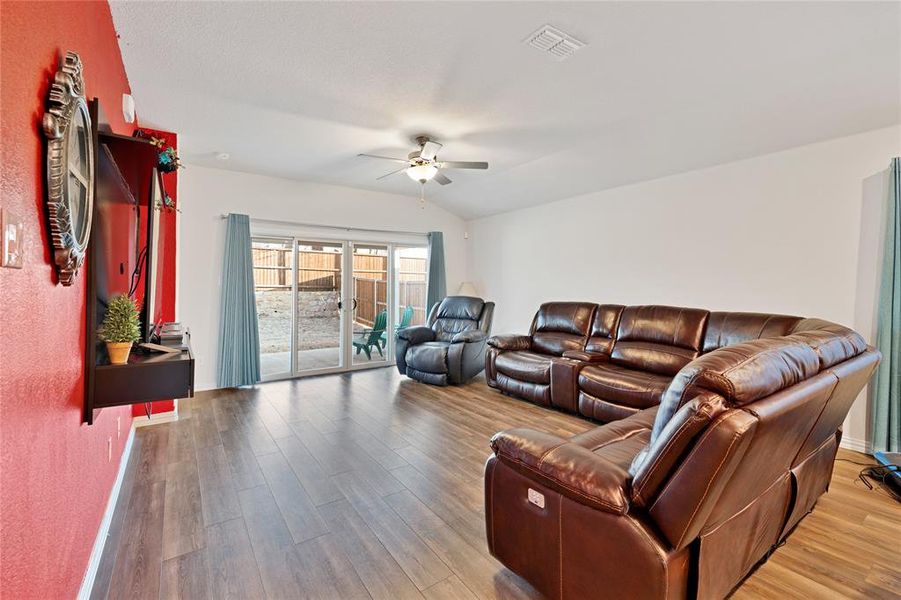 Living area with visible vents, wood finished floors, a ceiling fan, and vaulted ceiling