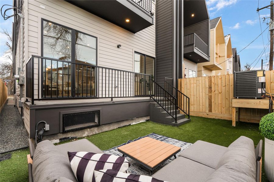An elevated deck transitions effortlessly to a turfed yard below, offering a polished, low-maintenance setting for outdoor lounging.