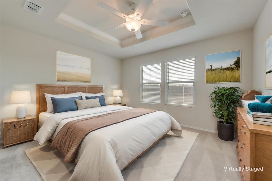 Carpeted bedroom with ceiling fan and a raised ceiling